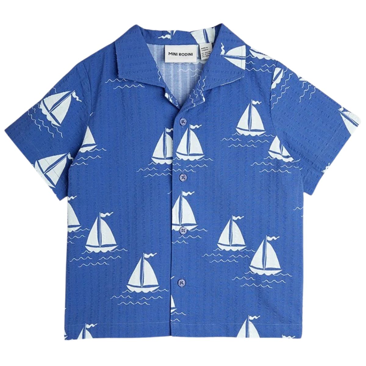 The Sailing Boats Woven Shirt from Mini Rodini. Short-sleeved shirt with an all-over sailor boat print, and button-down front.