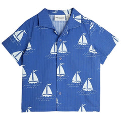 The Sailing Boats Woven Shirt from Mini Rodini. Short-sleeved shirt with an all-over sailor boat print, and button-down front.