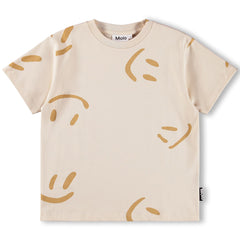 The Riley Tee by Molo, short-sleeve kids T-shirt with all-over abstract smiley face motifs on a light neutral background.