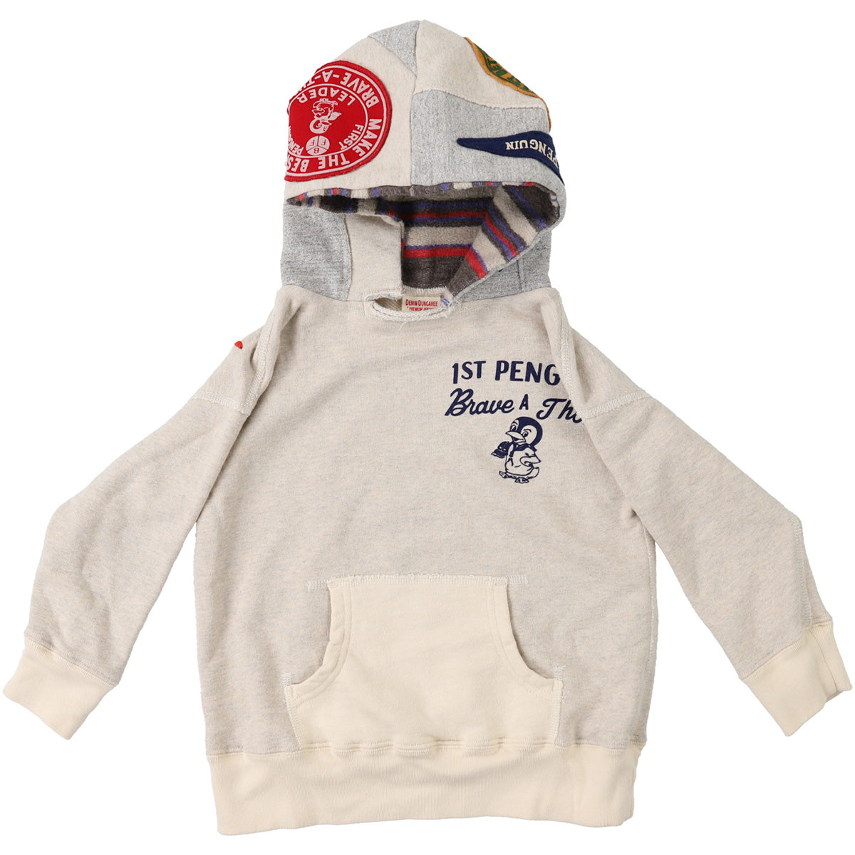The Pile Pennie Patch Parka from Denim Dungaree. Beige hoodie with contrast patchwork hood featuring badge motifs.