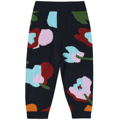 The Baby Jaquard Pants from FUB. Colorful floral-patterned pants on a black background.