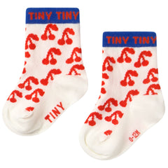 The Cherries Medium Socks from Tiny Cottons. Pair of socks with red cherries patterns and blue bands labeled.