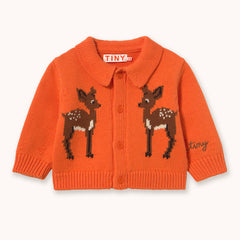 An orange knit cardigan sweater for toddlers and babies by designer Tiny Cottons, featuring two knitted brown and white deer motifs on the front, a button-up front, and a small embroidered 'tiny' script on the left sleeve. The brand label 'TINY' is visible inside the collar.