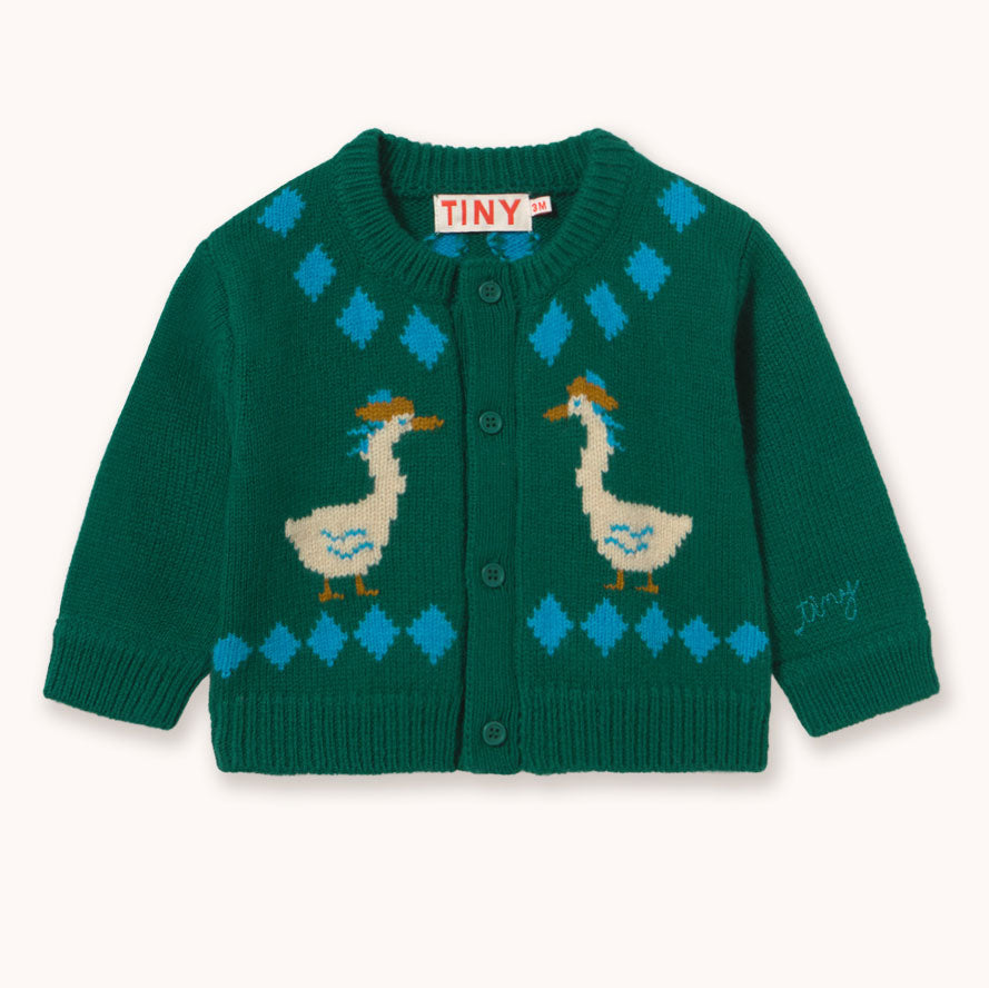 A green knit cardigan sweater by designer Tiny Cottons with blue diamond patterns and two cream-colored ducks with orange beaks, shown flat on a light cream background. The brand label 'TINY' is visible inside the collar.