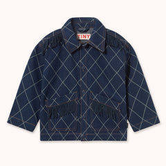 A navy blue denim jacket with a white argyle pattern and fringe details on the pockets and shoulders by designer Tiny Cottons shown flat against a light cream background. The brand label inside the collar reads 'TINY'.