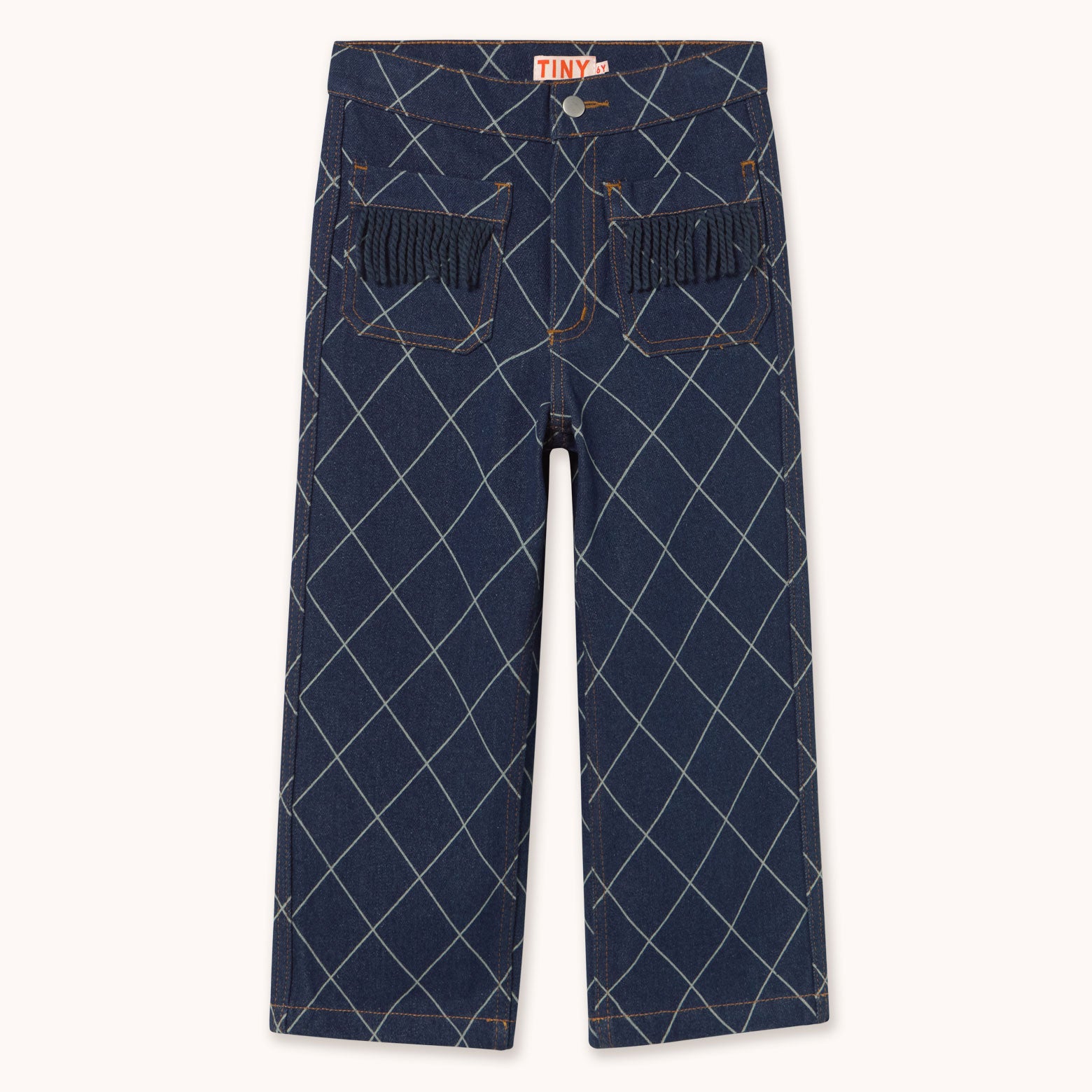A pair of dark blue denim pants featuring a white argyle pattern and fringed pocket details by designer Tiny Cottons, shown flat against a light cream background.