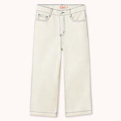 A pair of off-white denim jeans by designer Tiny Cottons with contrasting dark blue stitching, featuring a straight-leg or cropped fit and the brand name 'TINY' printed in red on the inner waistband, shown against a solid off-white background.