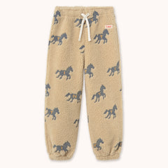 Beige sherpa fleece jogger pants by designer Tiny Cottons with an all over dark gray horse print, featuring a white drawstring and a small red 'TINY' brand tag on the side.