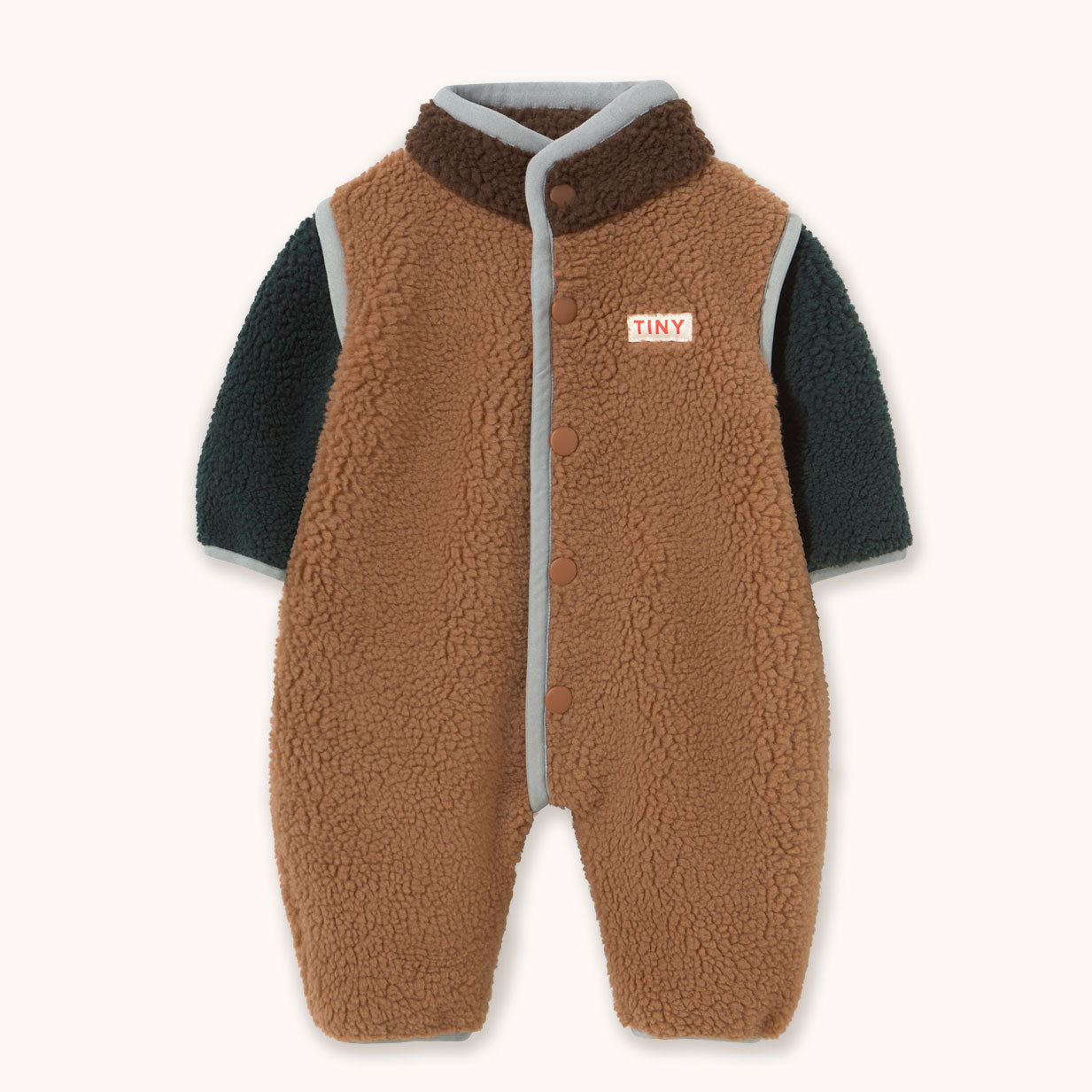 A baby fleece sleeper by designer Tiny Cottons with a brown sherpa vest body, dark teal long sleeves, and a gray trim, featuring a small 'TINY' brand patch on the chest.
