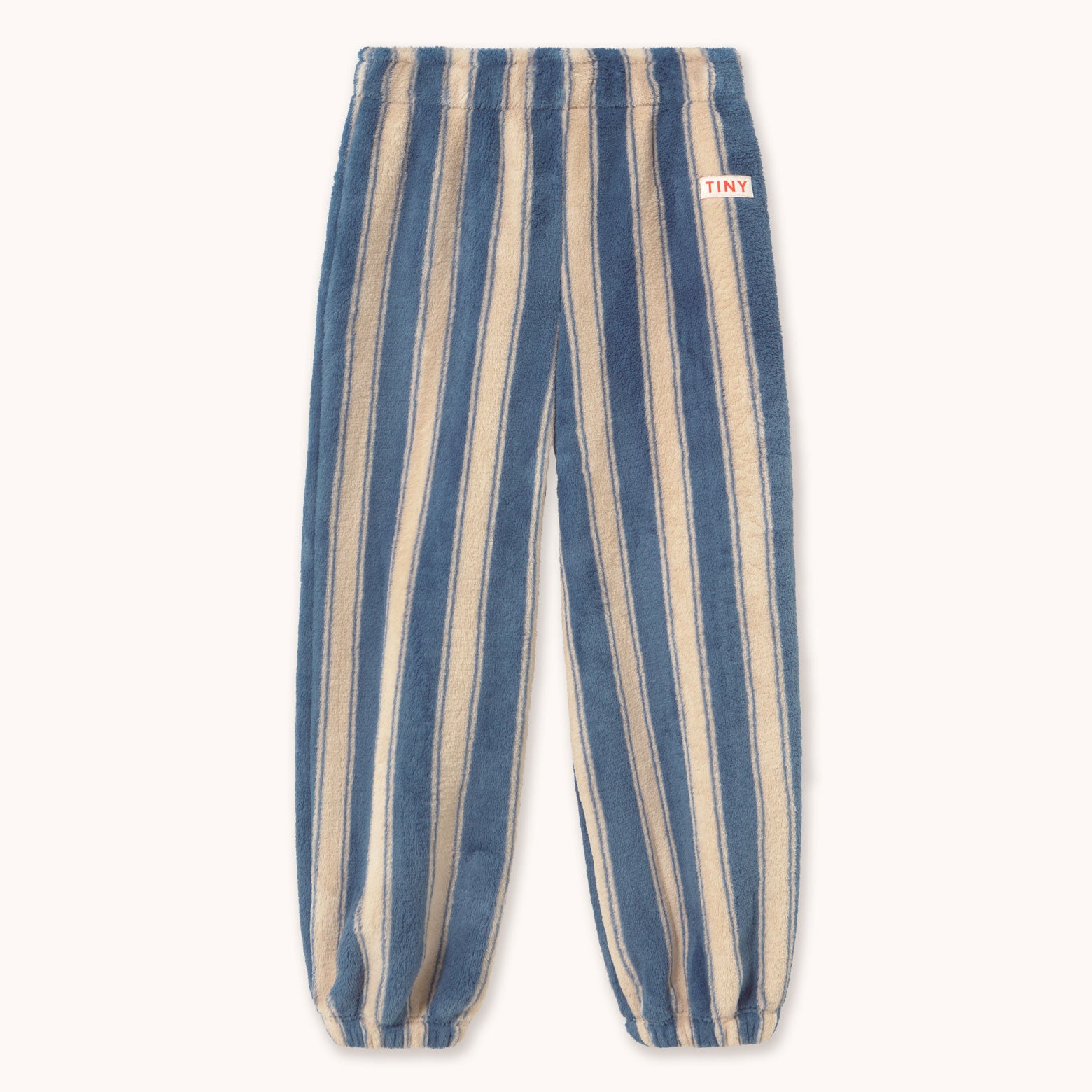 Blue and beige vertically striped fleece pants by designer Tiny Cottons with an elastic waistband and cuffs, featuring a small red and white 'TINY' brand patch on the upper right hip.