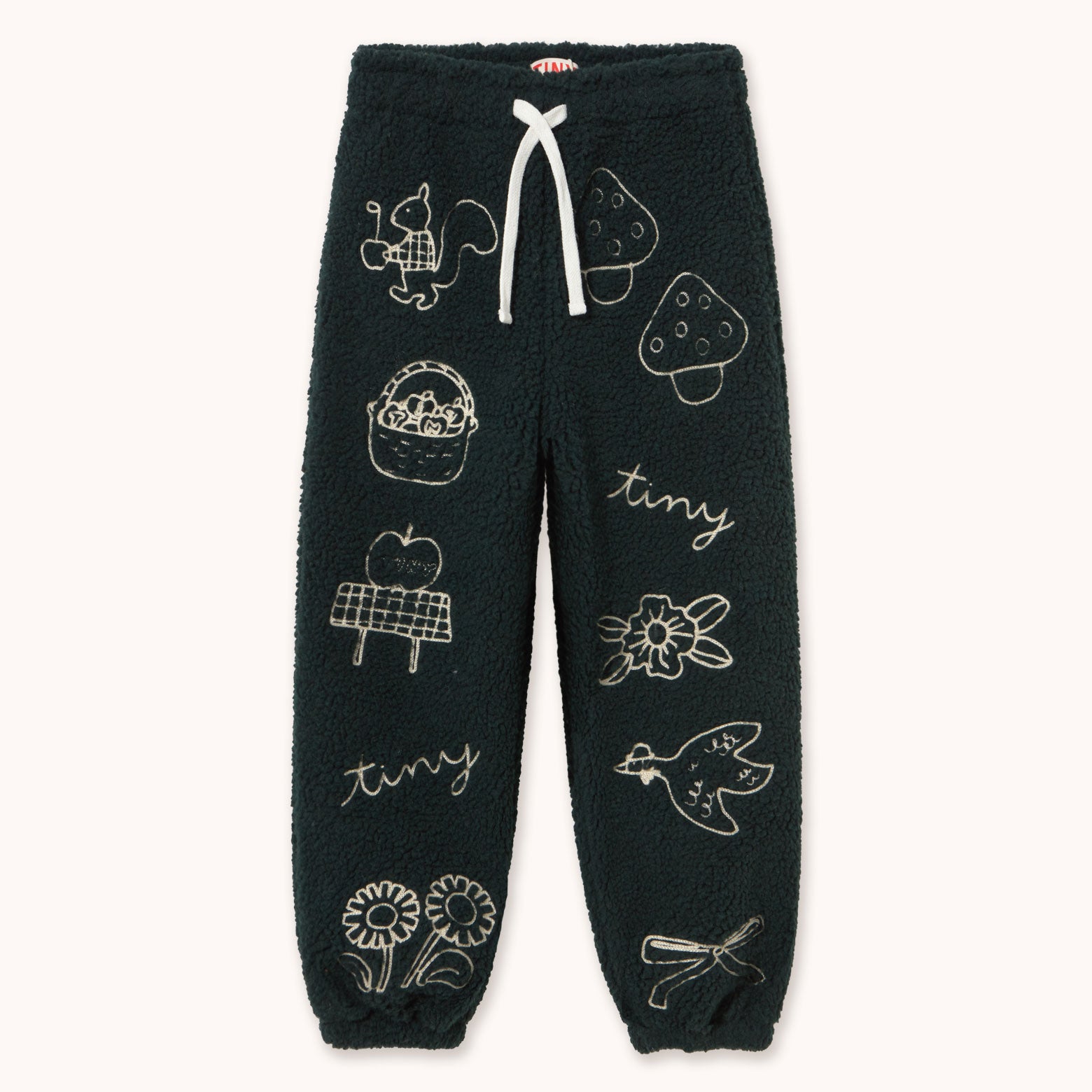 Dark forest green fleece jogger pants by designer Tiny Cottons with white embroidered illustrations of nature-themed motifs like a bird, strawberry, basket, apple, flowers, and the word 'tiny', featuring a white drawstring.