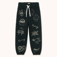 Dark forest green fleece jogger pants by designer Tiny Cottons with white embroidered illustrations of nature-themed motifs like a bird, strawberry, basket, apple, flowers, and the word 'tiny', featuring a white drawstring.