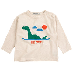 The Lake Monster Tee from Bobo Choses in heather beige featuring a pixelated green lake monster graphic and shoulder snaps.