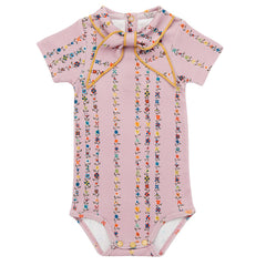 The Short Sleeve Scout Onesie from Misha & Puff. A delicate mauve romper adorned with colorful floral stripe patterns.