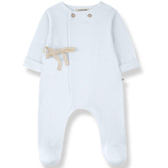 The Baptiste Jumpsuit from 1+ in the Family, a soft baby one-piece with shoulder buttons, tie detail, and footed legs.