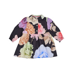 A long-sleeve children's dress with a black base and a large multicolor floral print, featuring a collar, button front, and gathered waist seam, shown on a plain white background. BY designer Christina Rohde