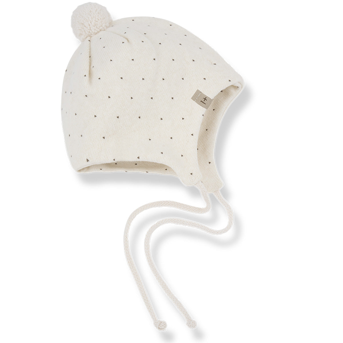 The Carlota Beanie from 1+ in the Family. Soft knit baby bonnet with subtle dotted pattern, pom-pom detail, and tie strings.