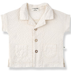 The Corinto Shirt from 1+ in the Family, a textured baby shirt with a collar, front buttons, and two patch pockets.
