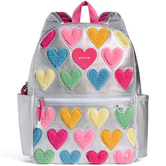 State Bags Kane Backpack in silver with colorful fuzzy heart patches, front zip pocket, and pink top handles