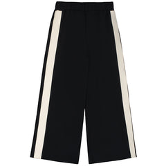 The Neoprene Pants from Little Creative Factory. Black wide-leg pants with cream-colored side stripes.