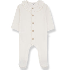 The Rosetta Jumpsuit from 1+ in the Family. A soft, long-sleeved baby onesie in ecru with a delicate ruffled collar.