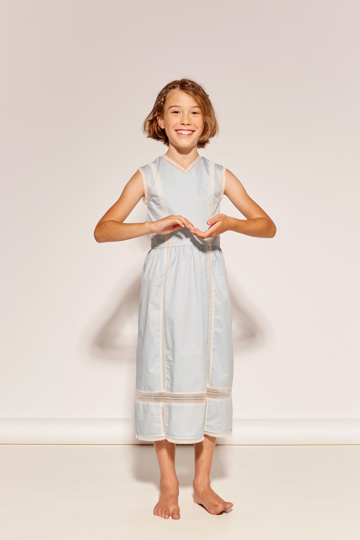 The Serenity Dress by The Middle Daughter in pale blue with lace trim and sleeveless midi silhouette.