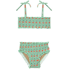 The Cherries Smock Swim Set from Tiny Cottons, two-piece swimsuit with smocked fabric, cherry print, and tie straps.