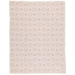 The Teddy Blanket from Bebe Organic featuring a knitted patchwork design with a signature bear motif and lace border trim.