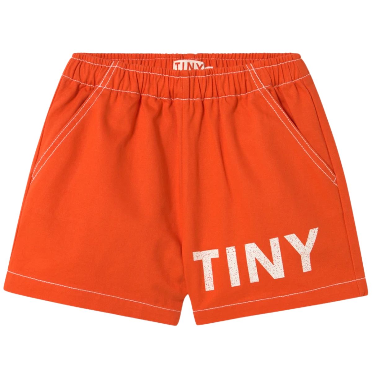The Solid Logo Short from Tiny Cottons. Bright red shorts feature a relaxed straight fit, an elastic waistband, and pockets.