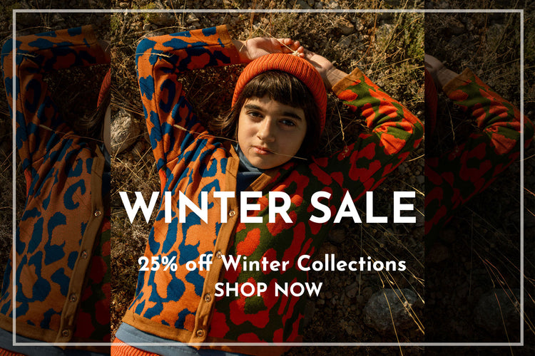 Girl wearing a colorful orange winter cardigan and hat with text overlay for a winter sale promotion - 25% off winter collections, shop now